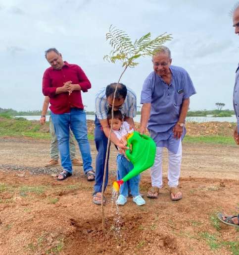 Rotarians planting tree with young child using green watering can
